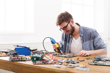 Fototapeta na wymiar Technician repairing motherboard by air dryer