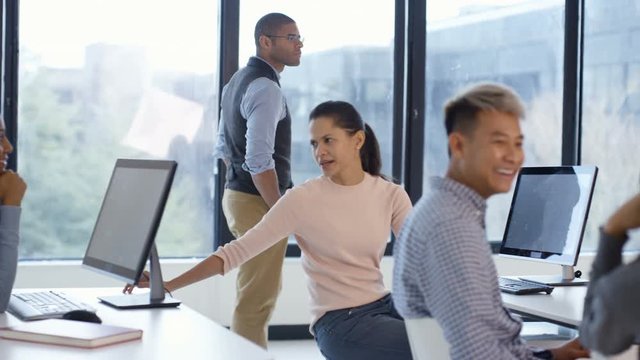  Students working on computers & listening to teacher in adult education class
