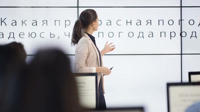 Adult students in language class with large screen showing Russian letters