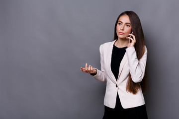 Young businesswoman has call. Studio shot on grey background
