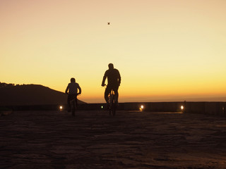 Father and son ridding bicycle in the sunset