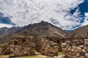 Incan ruins with mountain range backdrop.