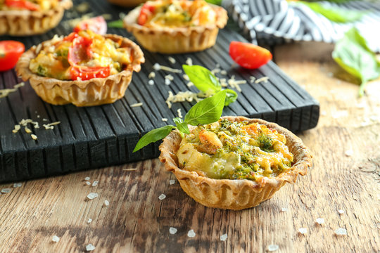 Delicious crispy tarts with broccoli on wooden table