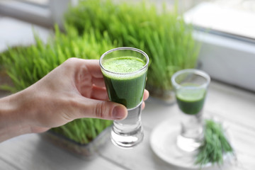 Hand of young man with shot of wheat grass juice
