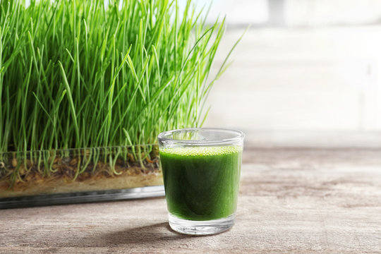 Shot of wheat grass juice on wooden table