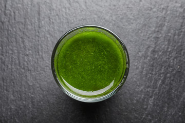 Shot of healthy wheat grass juice on slate plate