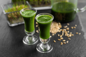 Shots of healthy wheat grass juice on slate plate