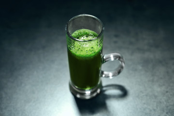 Shot of healthy wheat grass juice on table