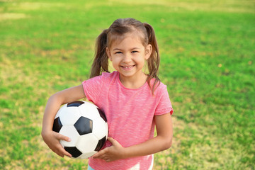 Naklejka premium Cute little girl holding ball outdoors