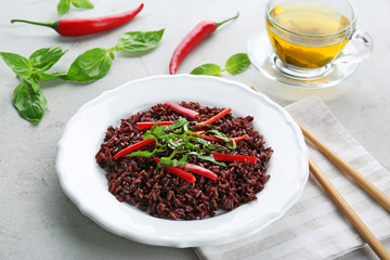 Plate with brown rice and vegetables on table