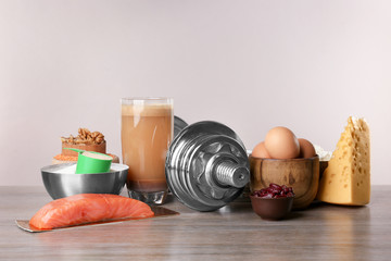 Composition with protein shake, food and dumbbell on table
