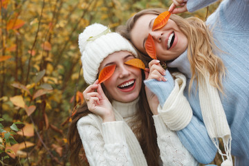 Beautiful girlfriends on the autumn background having fun. Cheerful women in the fall time. Smiling...