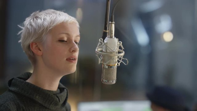  Close up female vocalist in recording studio singing into microphone
