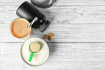 Glass with protein shake and powder on table