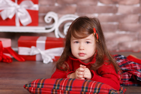 Young brunette dolly lady girl stylish dressed in red dress costume chequers check tartan skirt strap shoes smiling posing sitting in studio christmas tree with pout lips and pink cheeks.