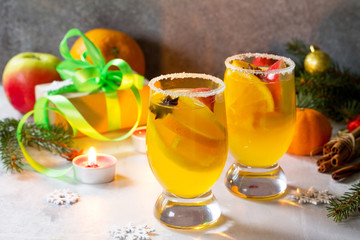 Homemade Christmas cocktail spicy white wine with cinnamon sticks, aniseed stars and pieces of fruit, served in two cups on a gray stone or slate. Copy space.