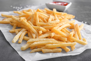 Yummy french fries on paper, closeup