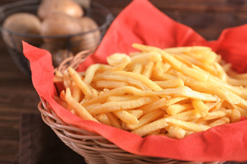 Basket with yummy french fries on table