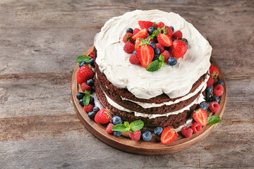 Delicious chocolate cake with berries on wooden table