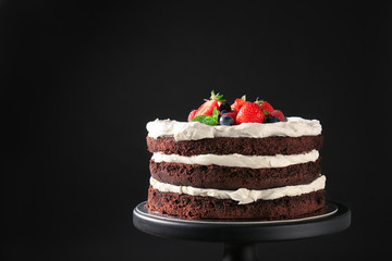 Dessert stand with delicious chocolate cake on black background