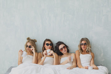 group of beautiful young woman napping in her bed after party in sunglasses. Sexy stylish young woman model lying in bed.