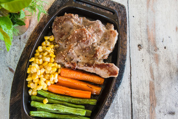 Pork steak with vegetable. Corn, carrots, green beans, on wooden table background.