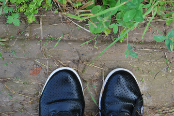 Black women's shoes, wet from the rain, on dirty wet ground, photographed from the top down