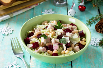 Homemade appetizer on a festive Christmas table. Salad with beets, Peking cabbage, meat and beans. Top view.