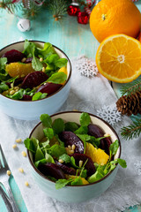 Homemade appetizer on a festive Christmas table. Salad with beets, orange, arugula and pine nuts.