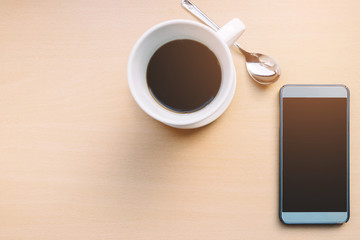 cup of coffee and smart phone from top view in the warm tone with sunlight