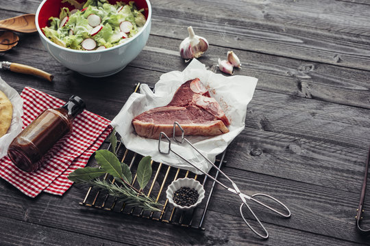 Food: Barbecue ingredients on dark wood with T-Bone Steak and salad