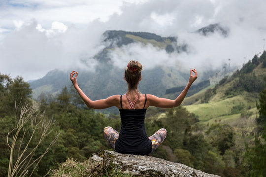 Frau meditiert auf Berg mit traumhafter Aussicht