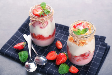 Jars of tasty strawberry dessert on table