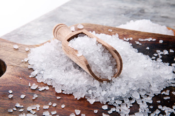 sea salt with wooden spoon and crystals of salt on wooden background.