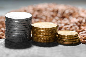 Stacks of coins and raw buckwheat on table. Price growth concept