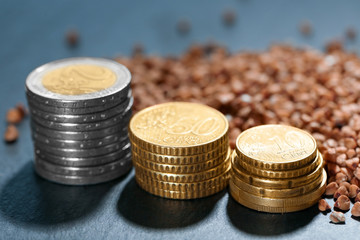 Stacks of coins and raw buckwheat on table. Price growth concept
