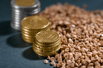 Stacks of coins and raw buckwheat on table. Price growth concept