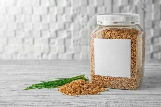 Jar with wheat grass seeds on table