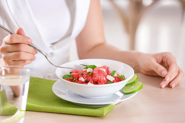 Obraz na płótnie Canvas Woman eating fresh salad with watermelon at table