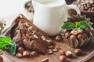 Piece of chocolate cake, mint leaves, hazelnuts and jar with milk