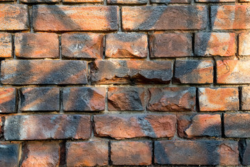 Background wall of an old red brick. In some places one can see traces of paint from a container