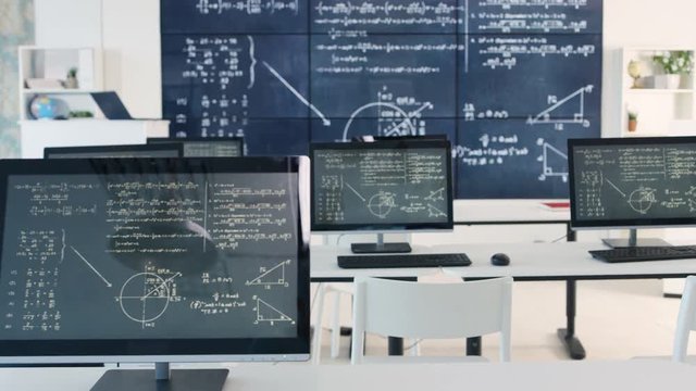  Interior of empty classroom with computers & math formulas on blackboard