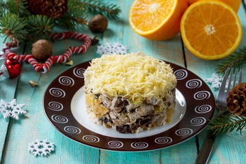 Homemade appetizer on a festive Christmas table. Salad with chicken, orange, prunes, cheese and walnuts.