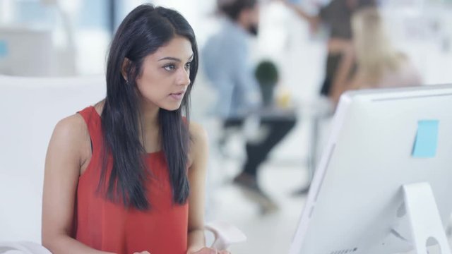  Young businesswoman working on computer with colleagues in a meeting