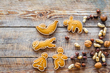 Healthy food for sportsman. Cookies in shape of yoga asanas near nuts on wooden background top view...