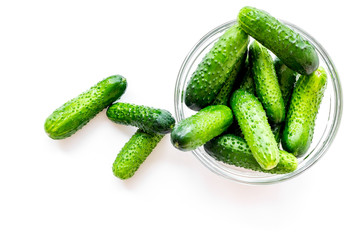 Fresh cucumbers in bowl on white background top view copyspace