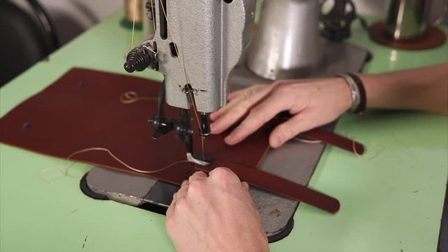 The process of making leather notebook. Craftsman stitching straps on sewing machine