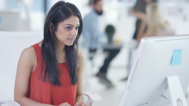  Young businesswoman working on computer with colleagues in a meeting