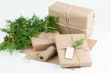 presents wrapped in brown paper on a white background with greenery