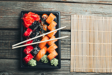 on a wooden table in the black container are nicely decomposition sushi